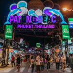 Lively Patong Beach nightlife scene with neon signs and people enjoying the bars.