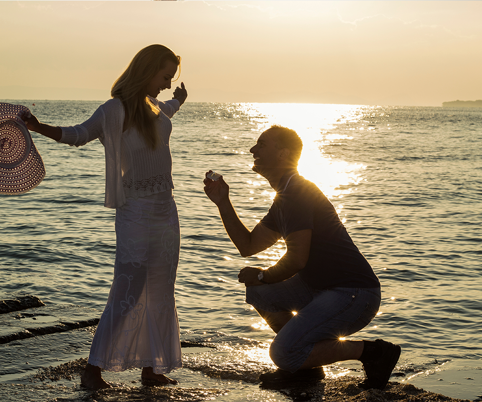 A man proposing to his partner at sunset on a romantic beach in Phuket, Thailand, with a stunning sea view.