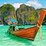 Traditional longtail boat on the Andaman Sea in Phuket during sunset, with vibrant orange and purple skies.